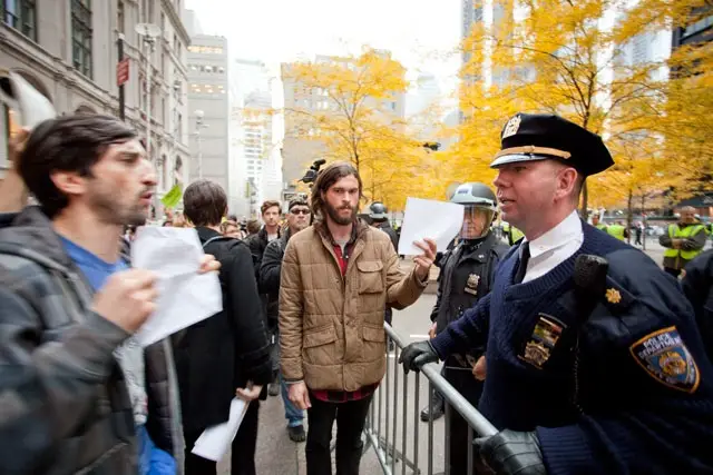 A protester shows an NYPD officer a copy of a restraining order earlier today.